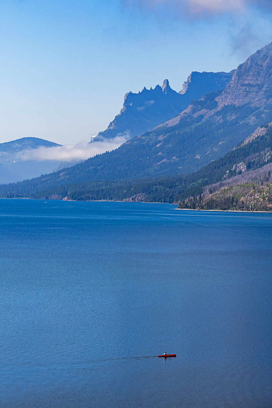 Upper Waterton Lake (and kayaker) with the International boundary and Montana in the distance.